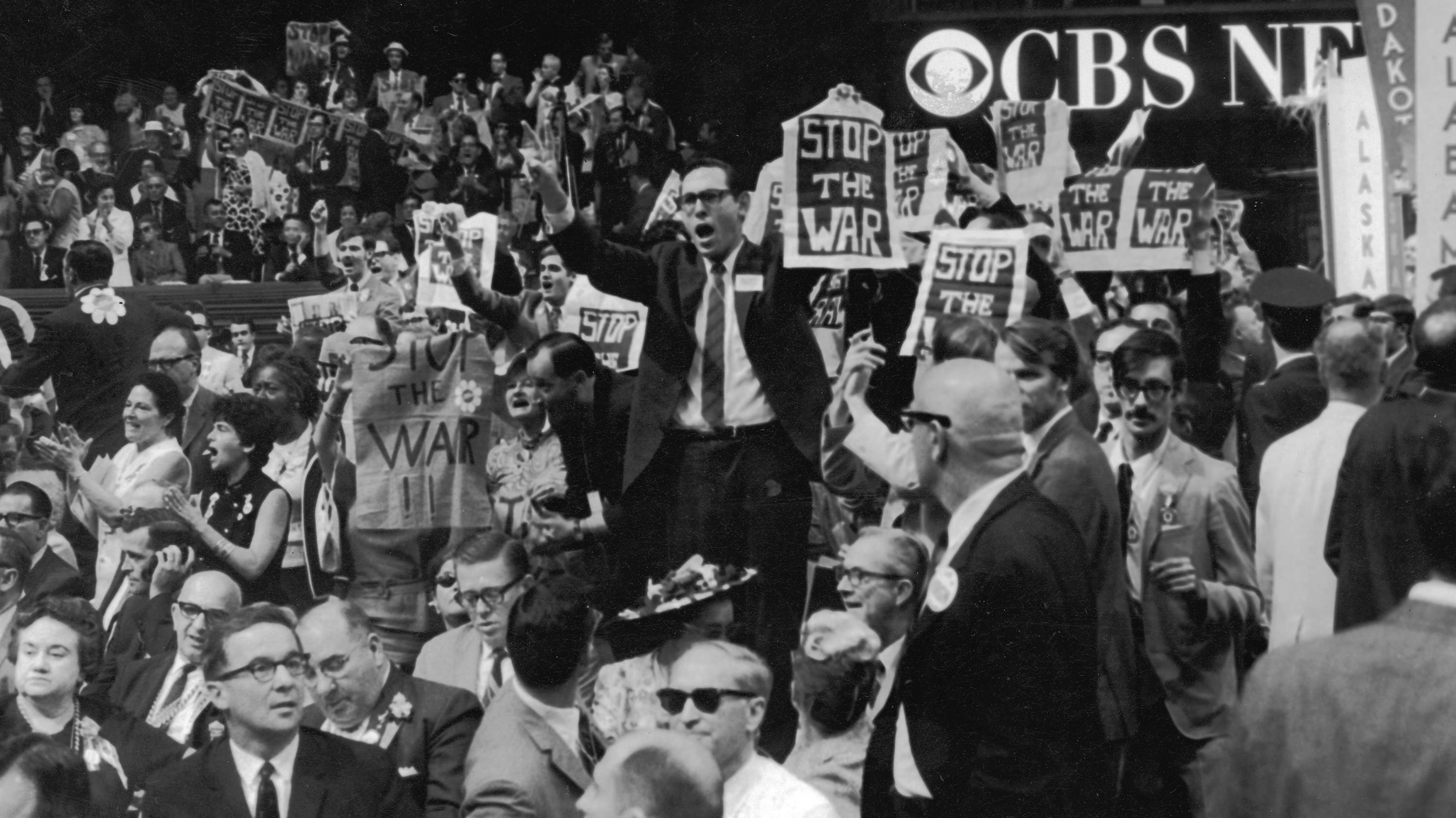 A crowd of delegates in the 1968 Democratic Convention convention holding up the signs that say Stop the War